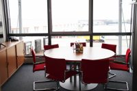 Meetingraum mit Tisch und roten Stühlen